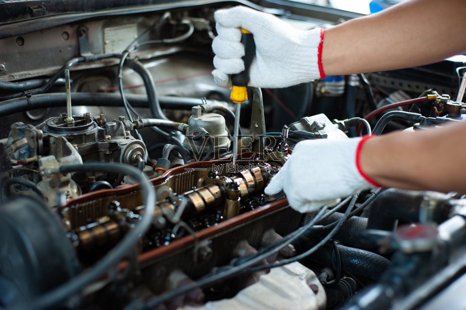 机修工正在修理和调试汽车的引擎。照片摄影图片