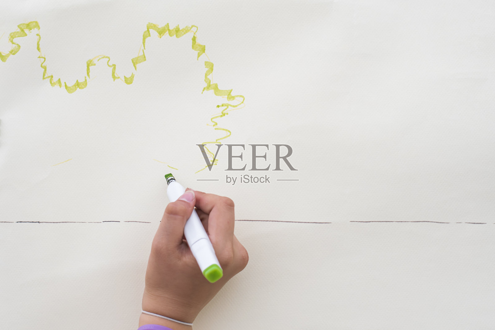 女性用绿色记号笔在纸上画出波浪线。未来的草图。照片摄影图片