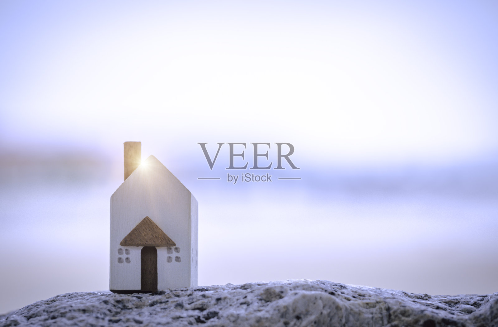 以海滩为背景的石头上的微型白色房子。家庭生活方式和建筑或租赁概念。照片摄影图片