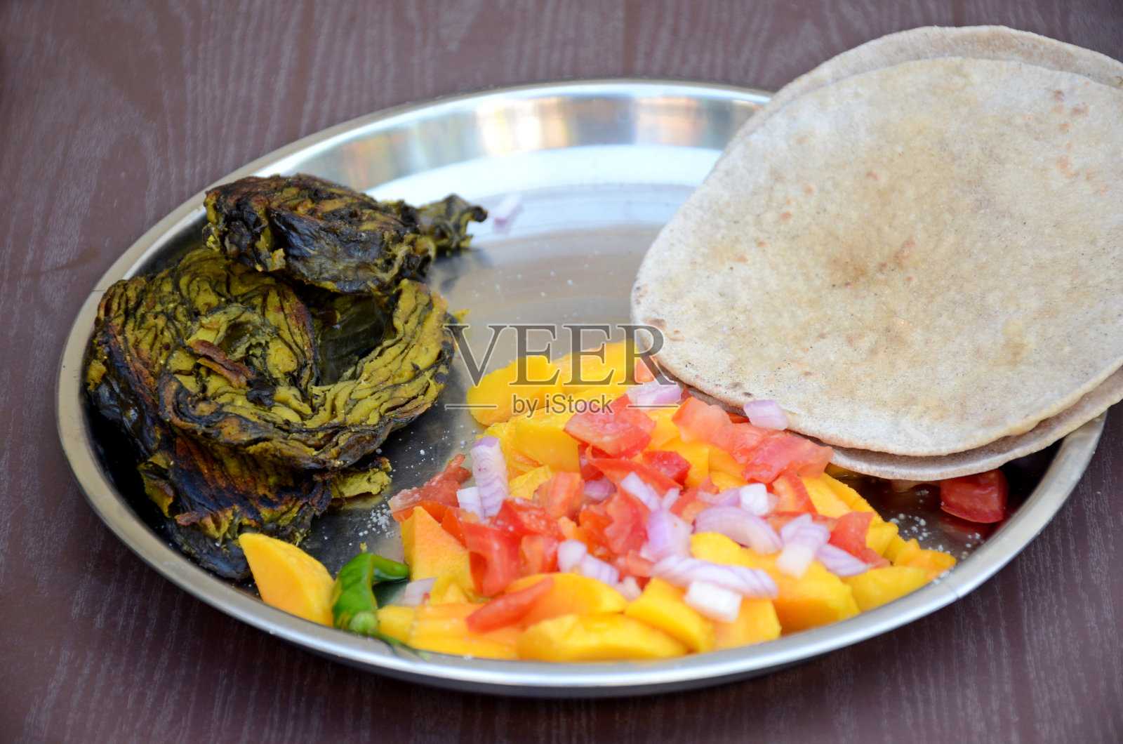 特写褐色的未发酵面包与油炸阿拉伯叶子，蔬菜，芒果，洋葱，西红柿，切成薄片，寒冷的棕色背景。照片摄影图片