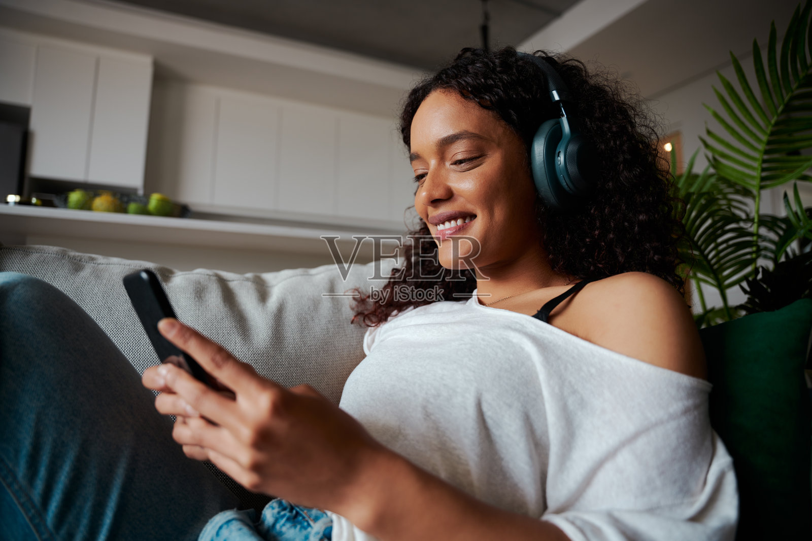 混血女学生在家工作，用手机发短信，听音乐照片摄影图片