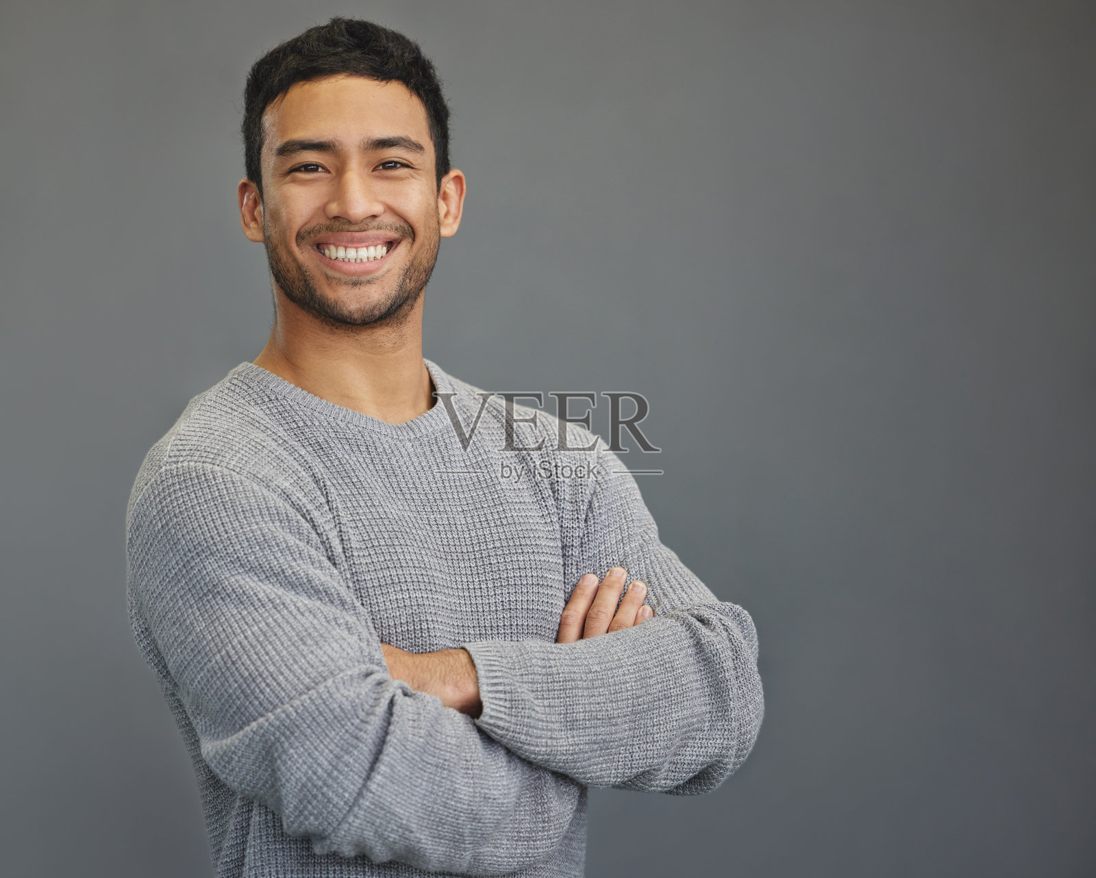 一个英俊的年轻人站在灰色的背景下照片摄影图片