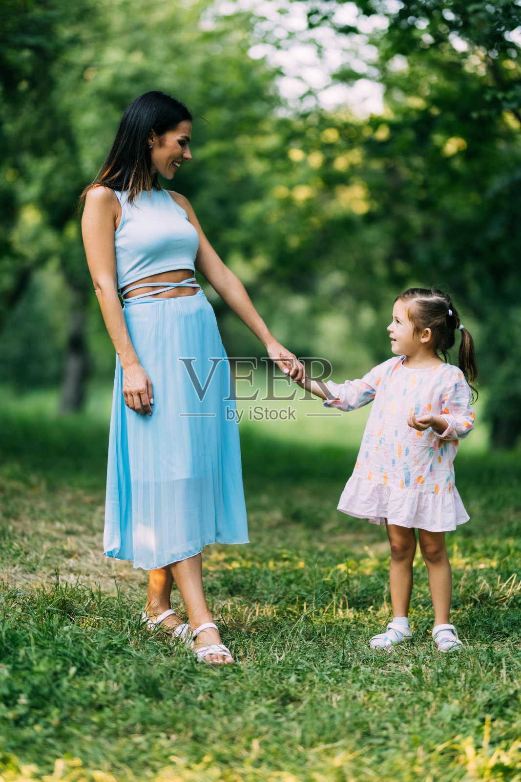 美丽的早晨，年轻的母亲和女儿在公园里玩耍和散步。照片摄影图片