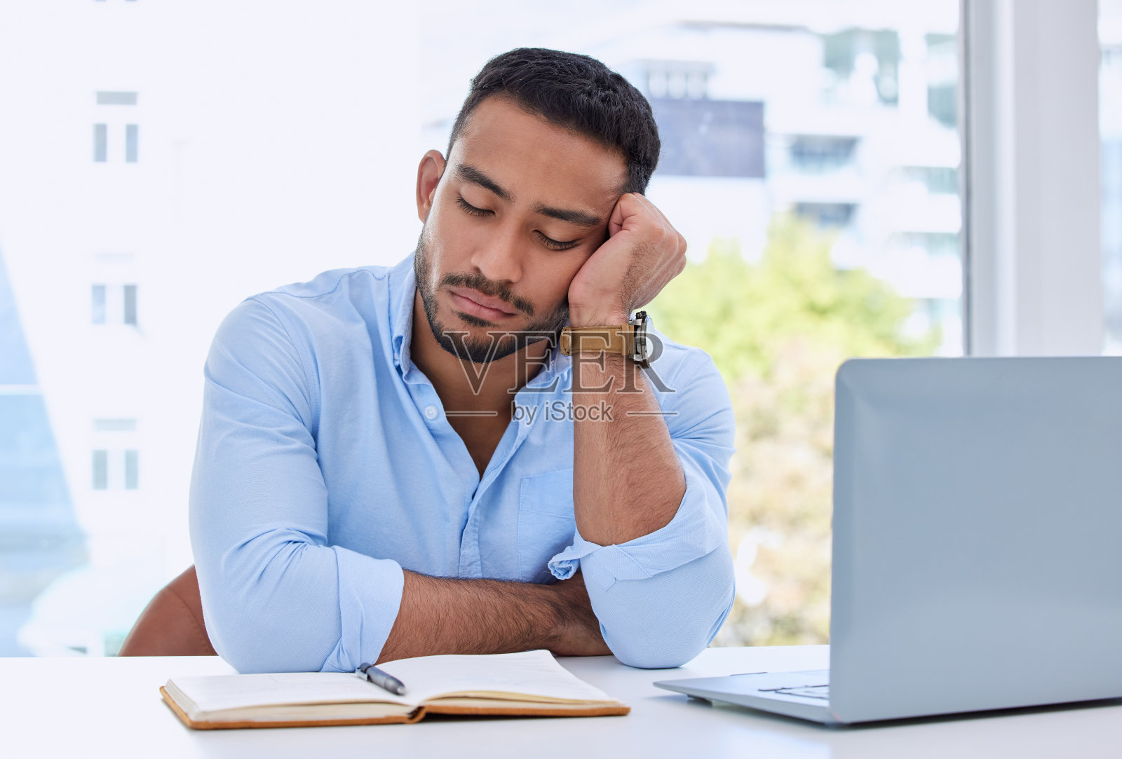 一个年轻的商人在他的办公室里打盹照片摄影图片