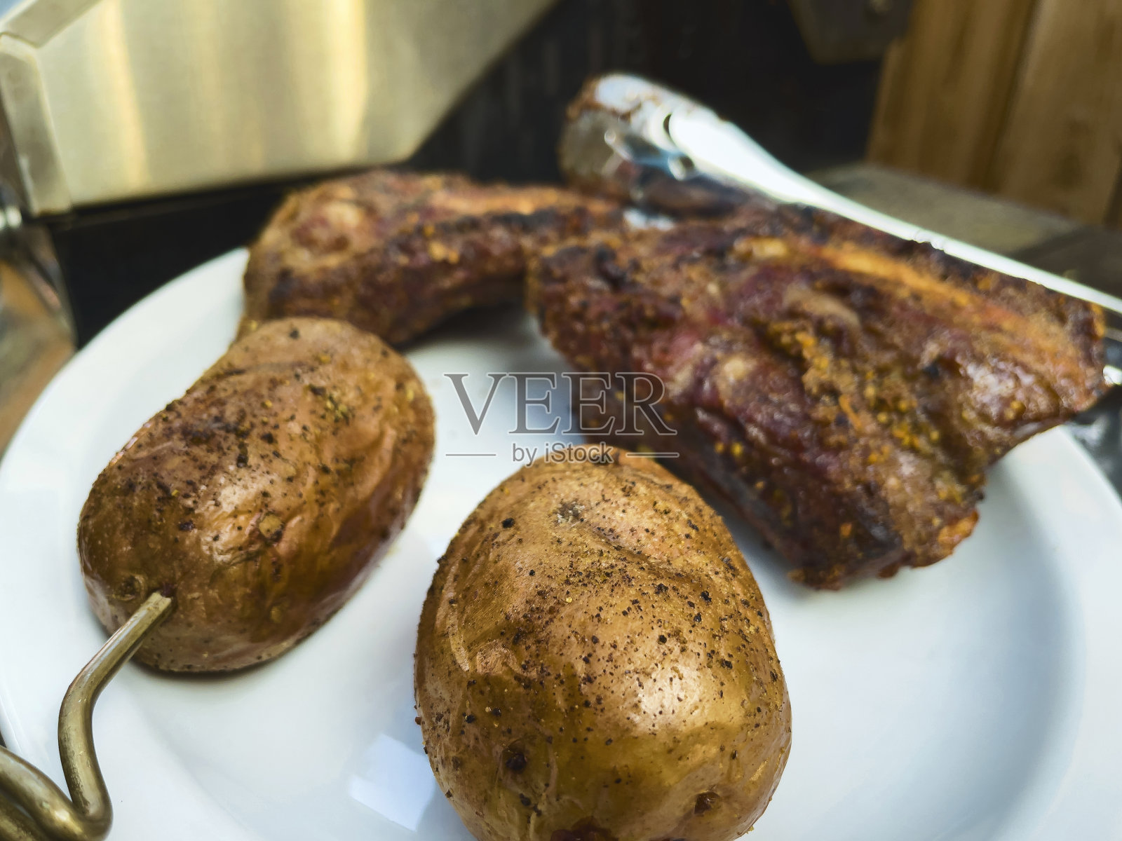 烧烤草饲料调味牛肉排骨和烤土豆白盘子照片系列照片摄影图片