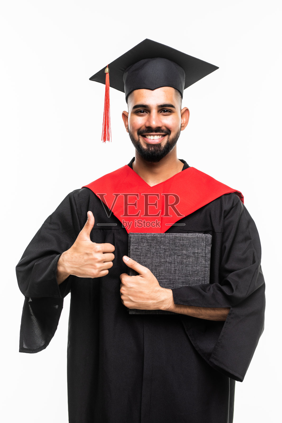 亚洲毕业生的男人戴着帽子和礼服微笑庆祝，展示大拇指自信的情绪，如此自豪和幸福的毕业日隔离在白色的背景照片摄影图片