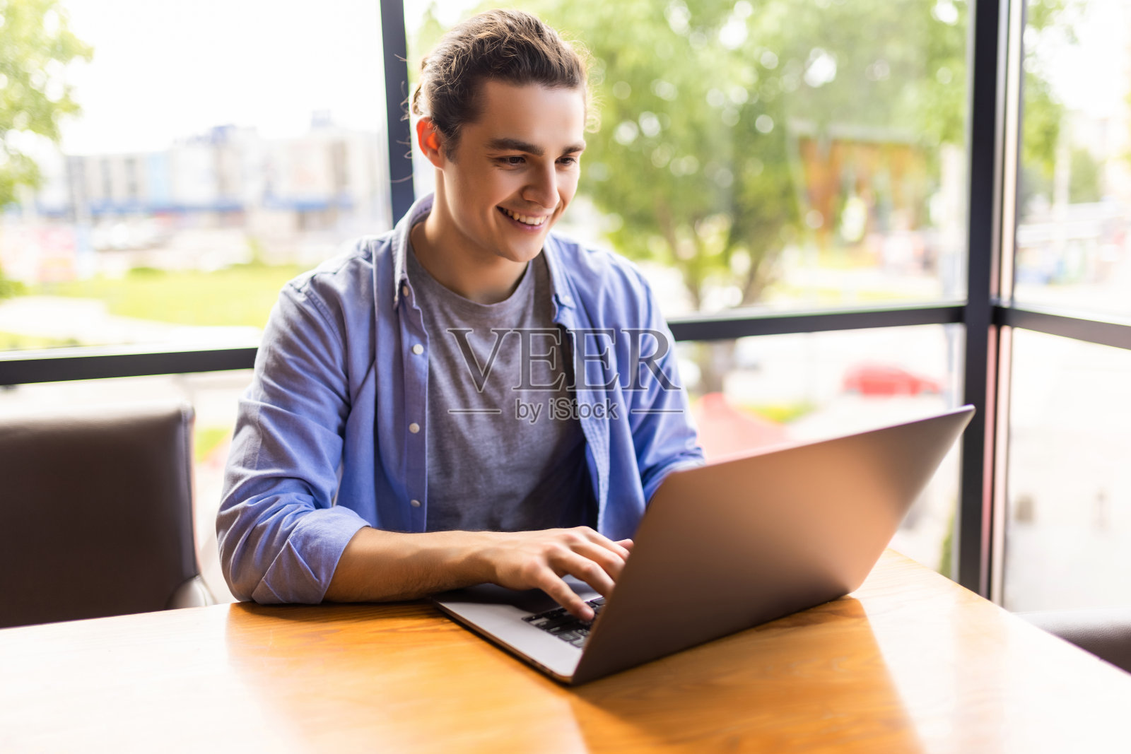 一个带着笔记本电脑在咖啡馆工作的帅哥照片摄影图片