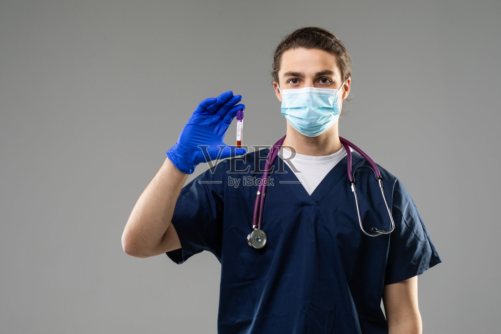 冠状病毒大流行病。冠状病毒的流行穿着防护服的人检查一个在灰色背景上分离的管中的病毒照片摄影图片