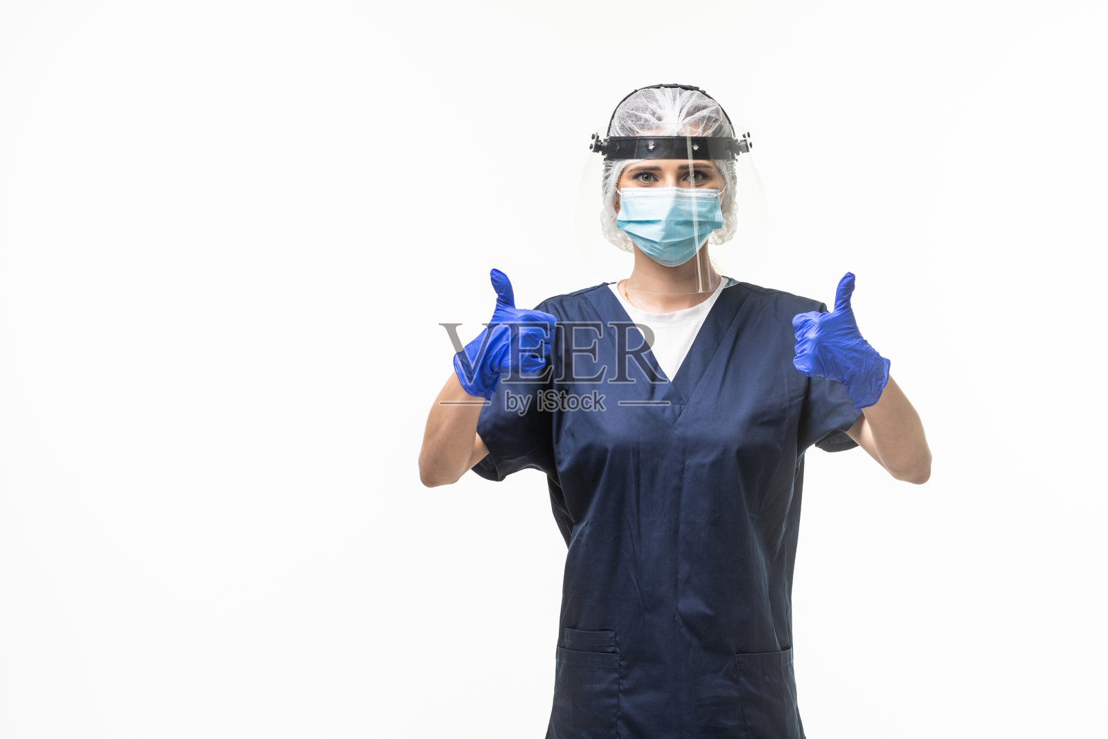 医学、保健和保护观念。护士身穿蓝色制服，戴着医用防护口罩，白色背景上竖起大拇指照片摄影图片