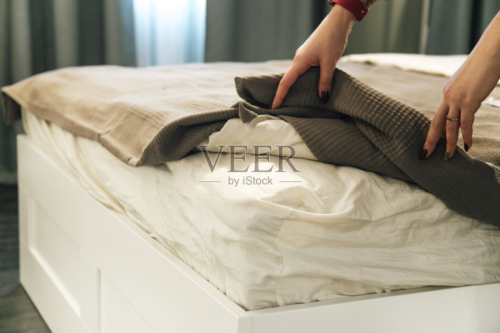 妇女正在把被套或床垫垫放在床上，或将被套或床垫垫放在床上进行清洗照片摄影图片