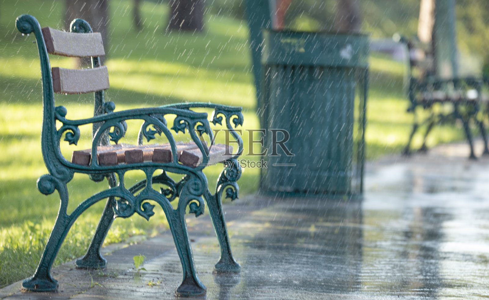 夏日公园里下雨时的绿色木凳。照片摄影图片