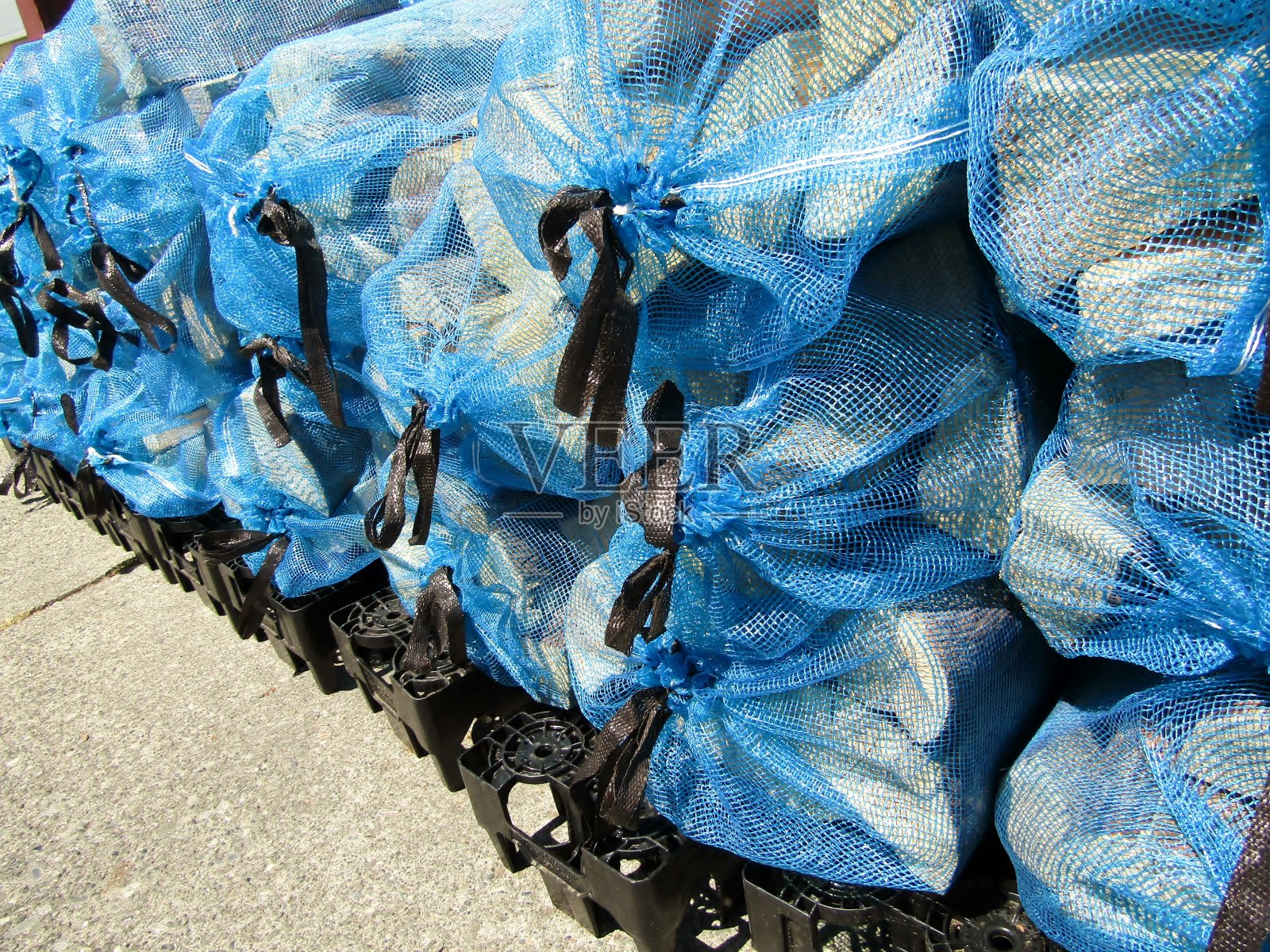 窑干原木堆在蓝色网袋与黑色拉胶带。照片摄影图片