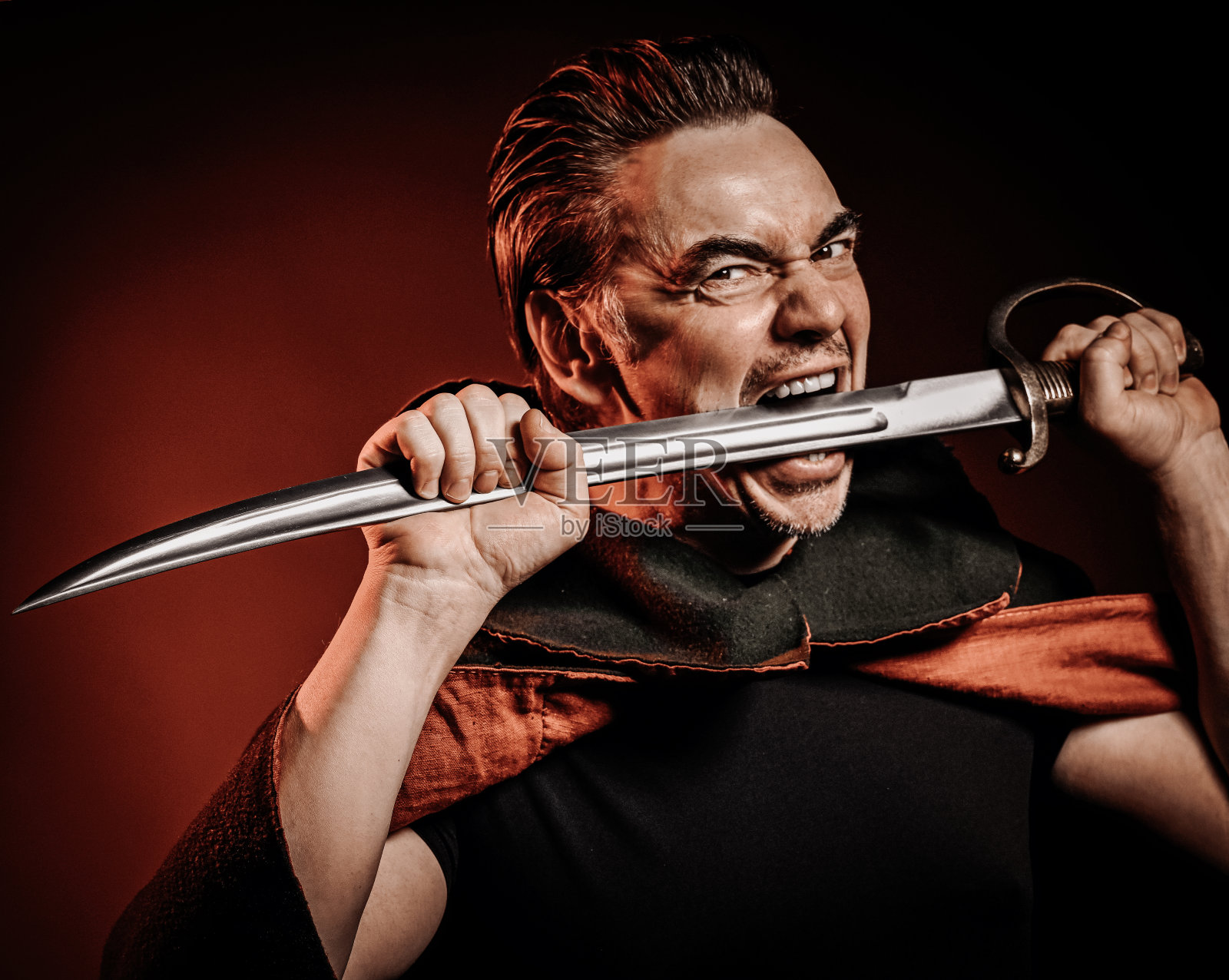 身披披风、骁勇善战的勇士，嘴里衔着军刀，准备为红袍而战照片摄影图片