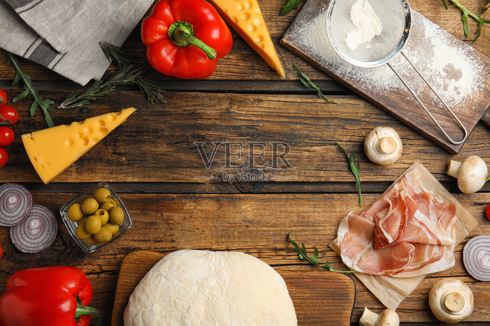 在木桌上平铺生面团和新鲜配料，留出文字空间。比萨配方照片摄影图片