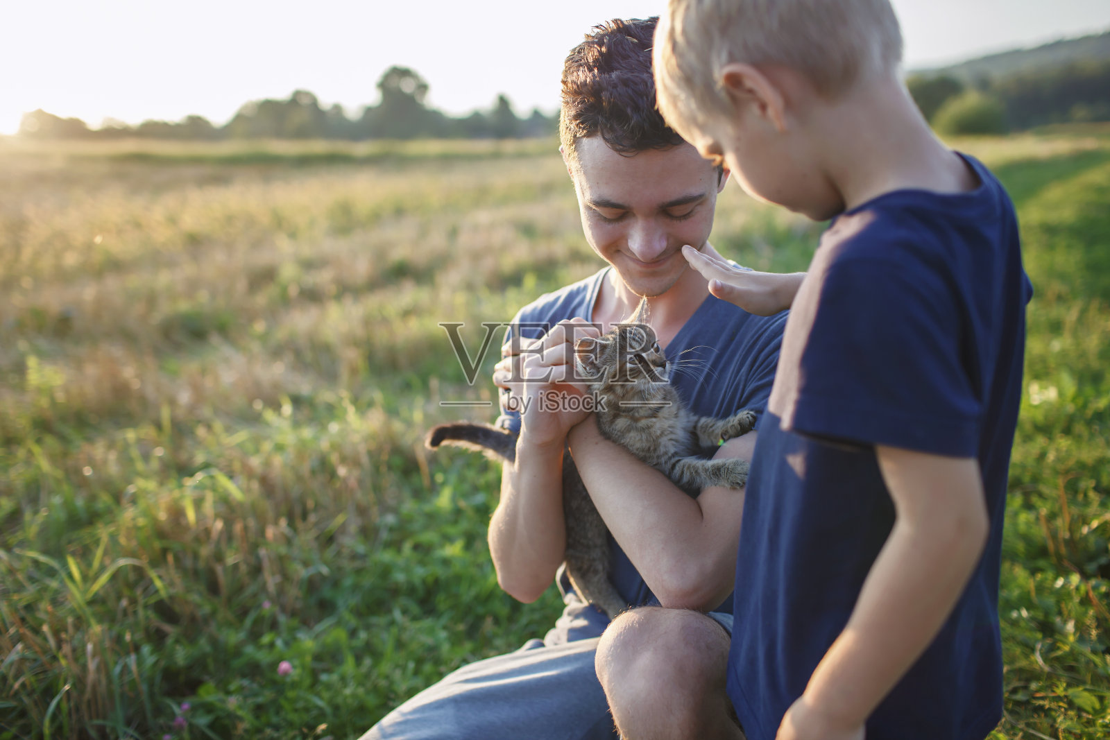 小伙子在野外散步时发现并捡起小猫，照顾无家可归的家养动物照片摄影图片