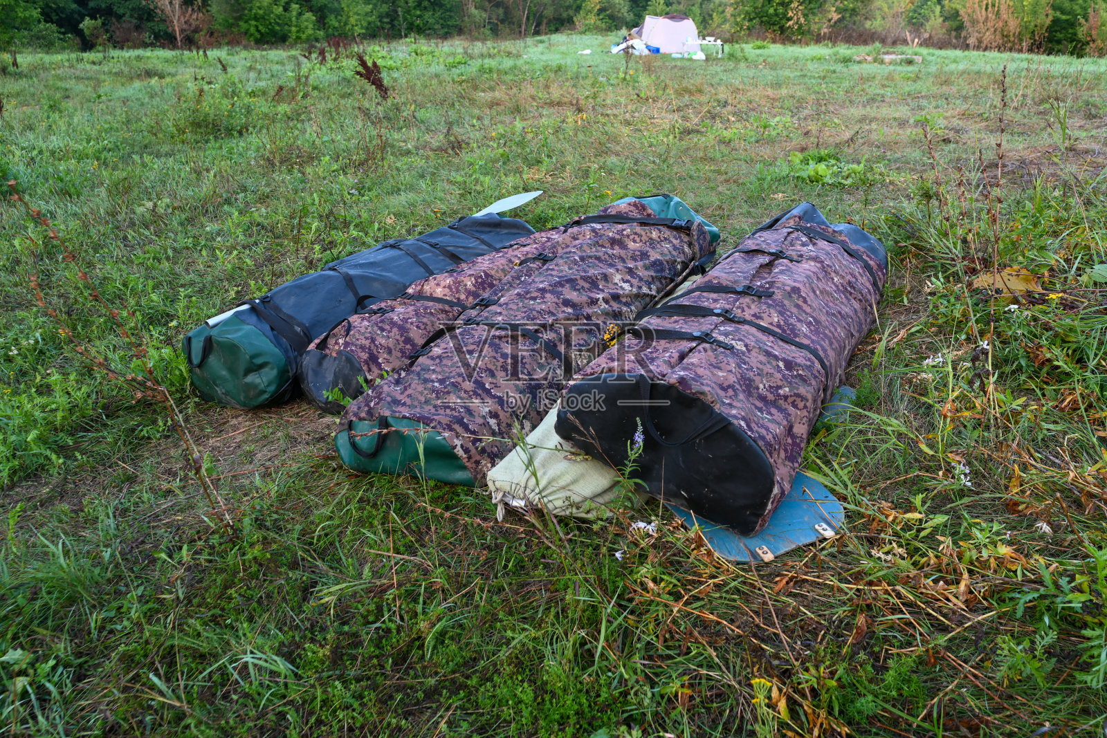 日出时，带着皮划艇的徒步旅行包在夏日田野的背景下。冒险旅游的生活方式。概念旅游热。活跃的周末假期，户外的野生自然。照片摄影图片