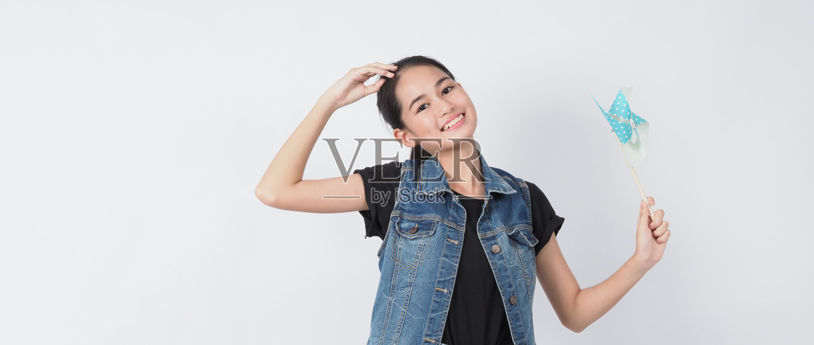 少女和纸风车玩具。肖像少年与蓝色纸风轮木棒手在白色背景摄影棚拍摄。代表风能，这是纯粹的能源和安全的地球。照片摄影图片