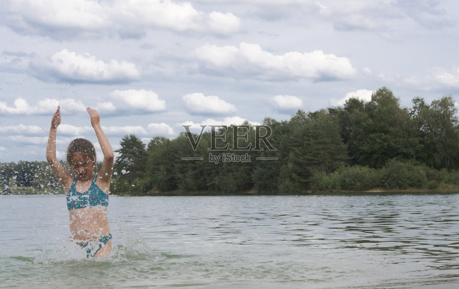 湖水里的女孩映衬着蓝天白云。泼水照片摄影图片
