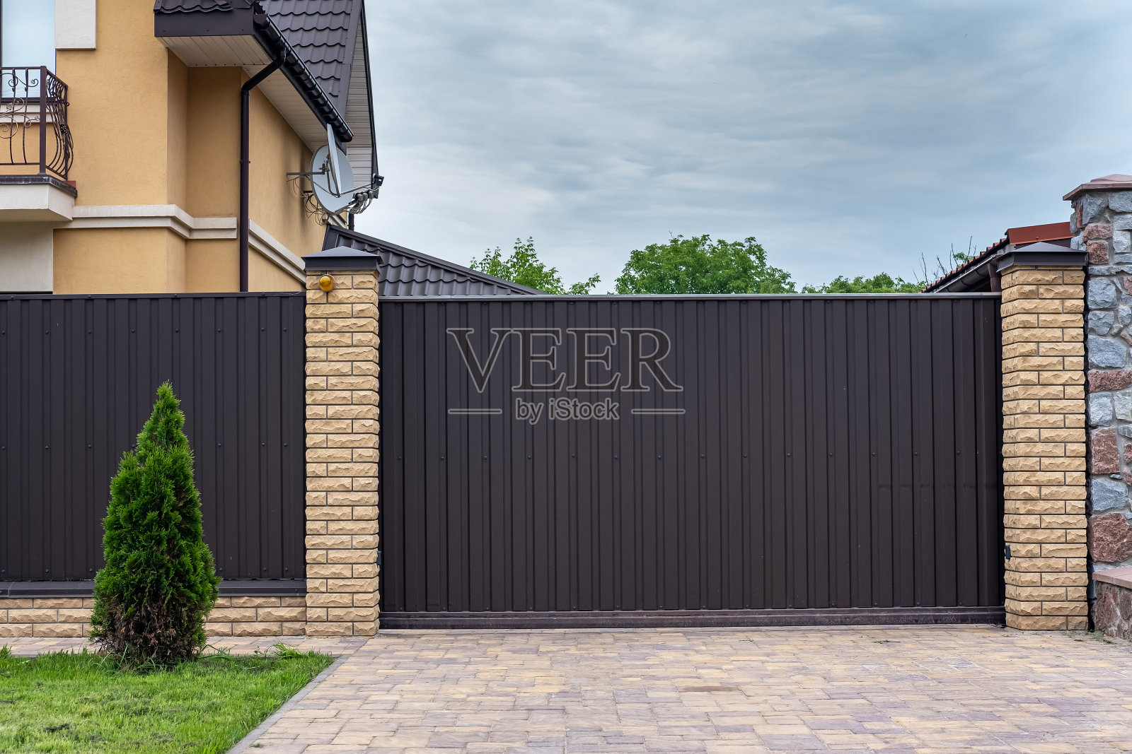 现代棕色波纹铁栅栏与装饰砖柱。照片摄影图片