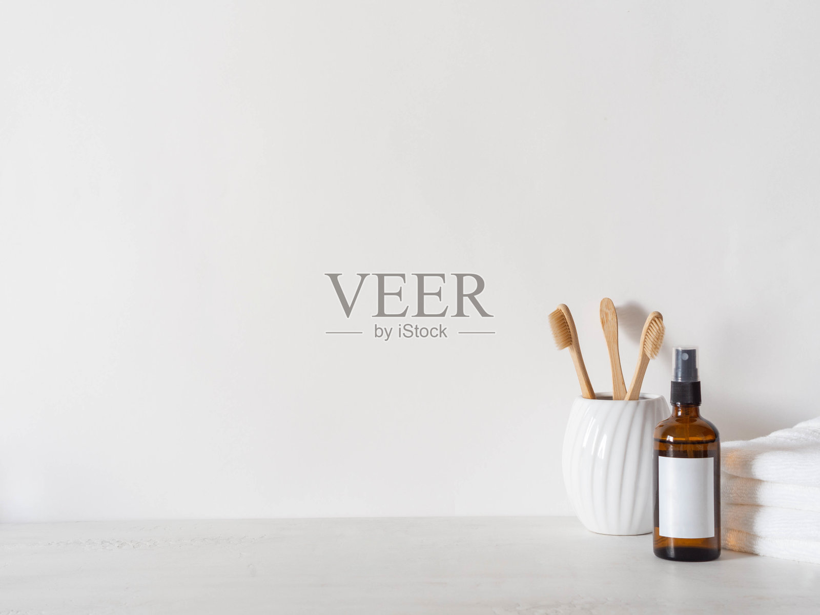 琥珀色玻璃瓶，白色标签，竹牙刷和白色毛巾照片摄影图片