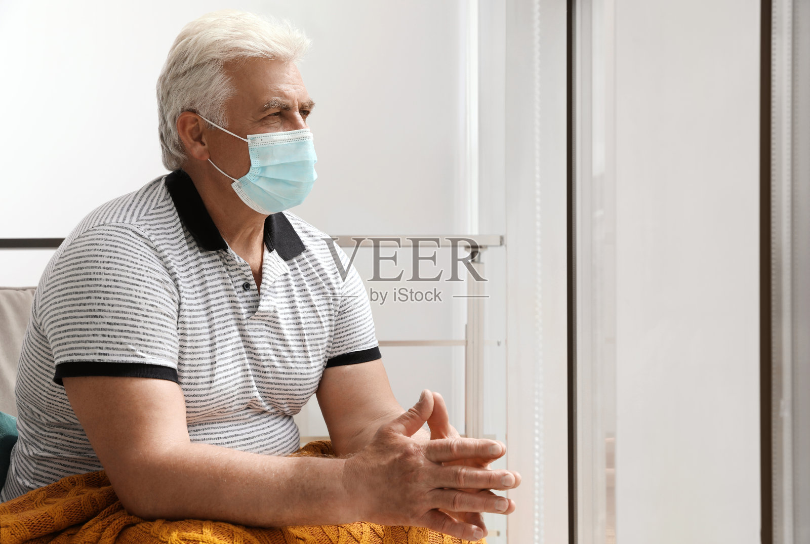 戴着防护口罩的老人躺在养老院的扶手椅上照片摄影图片