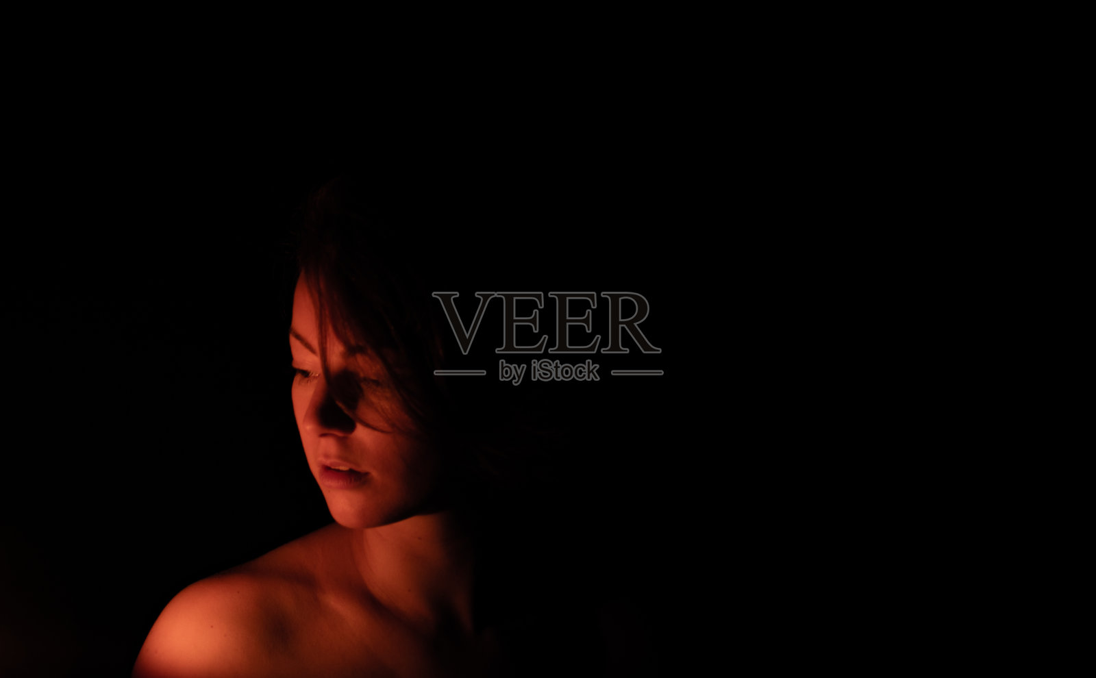 一名年轻女子暗而神秘的低调肖像，灯光效果，玩光，烛光，面具，大头照和特写。照片摄影图片