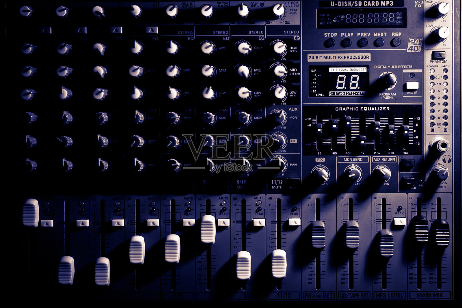 昏暗灯光下的专业混音控制台。照片摄影图片