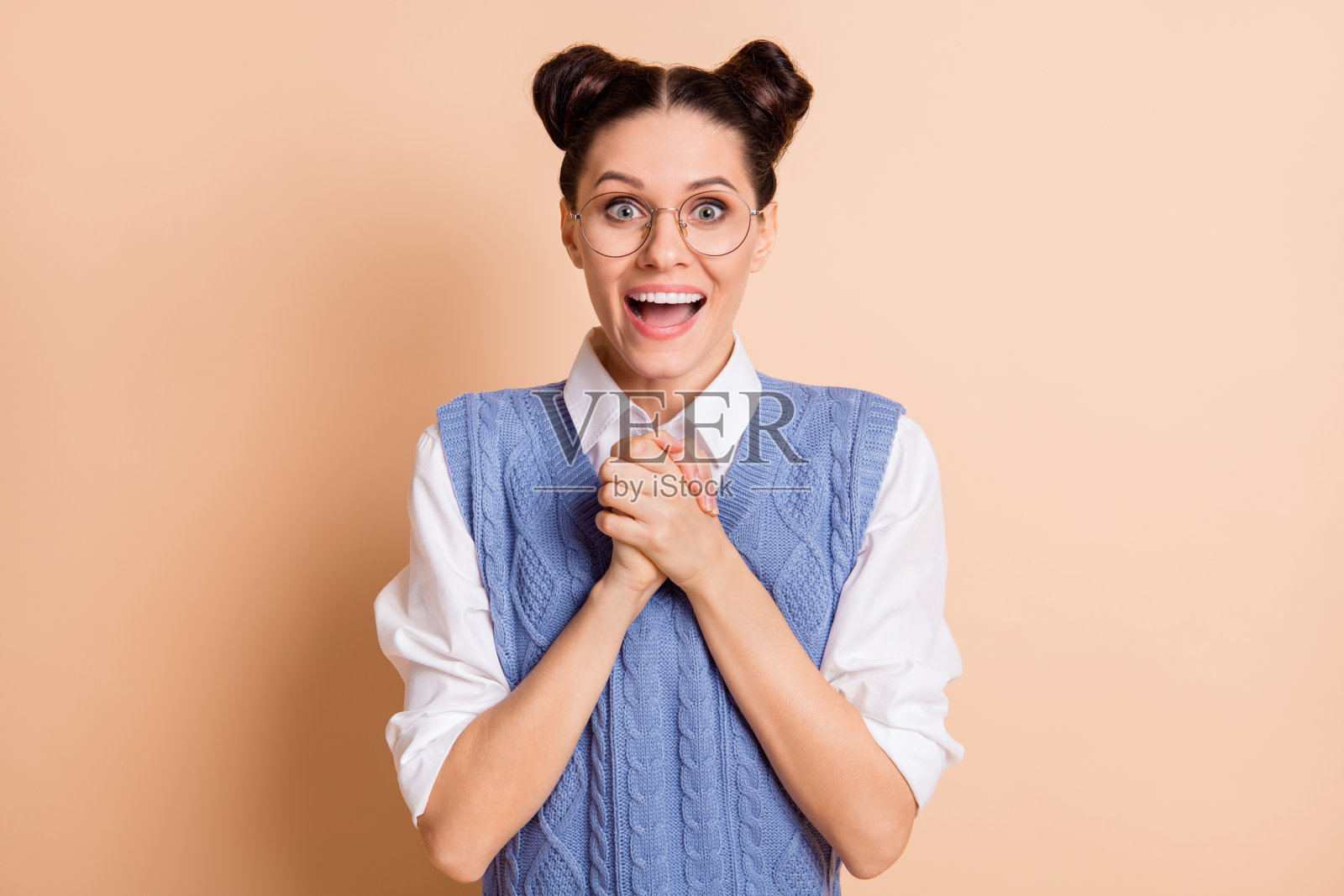 照片黑发印象不错的女士手牵手戴眼镜白色衬衫蓝色背心孤立在米色背景照片摄影图片