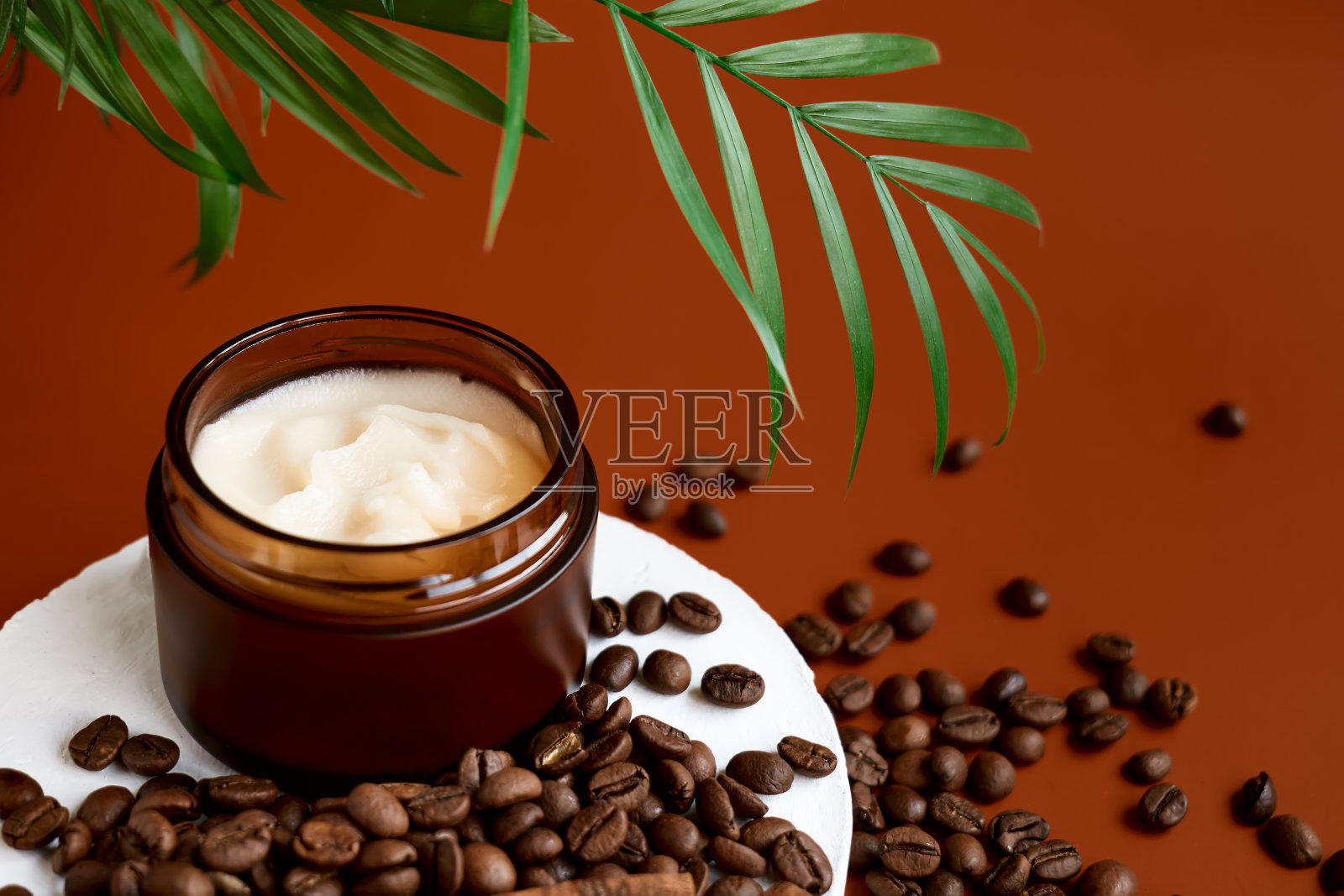 在白色石膏圆筒上打开的棕色奶油瓶展示，棕榈叶，咖啡豆和肉桂在柔和的深棕色背景上展示产品。抽象的基座。化妆品或美容产品推广时尚极简主义模型照片摄影图片