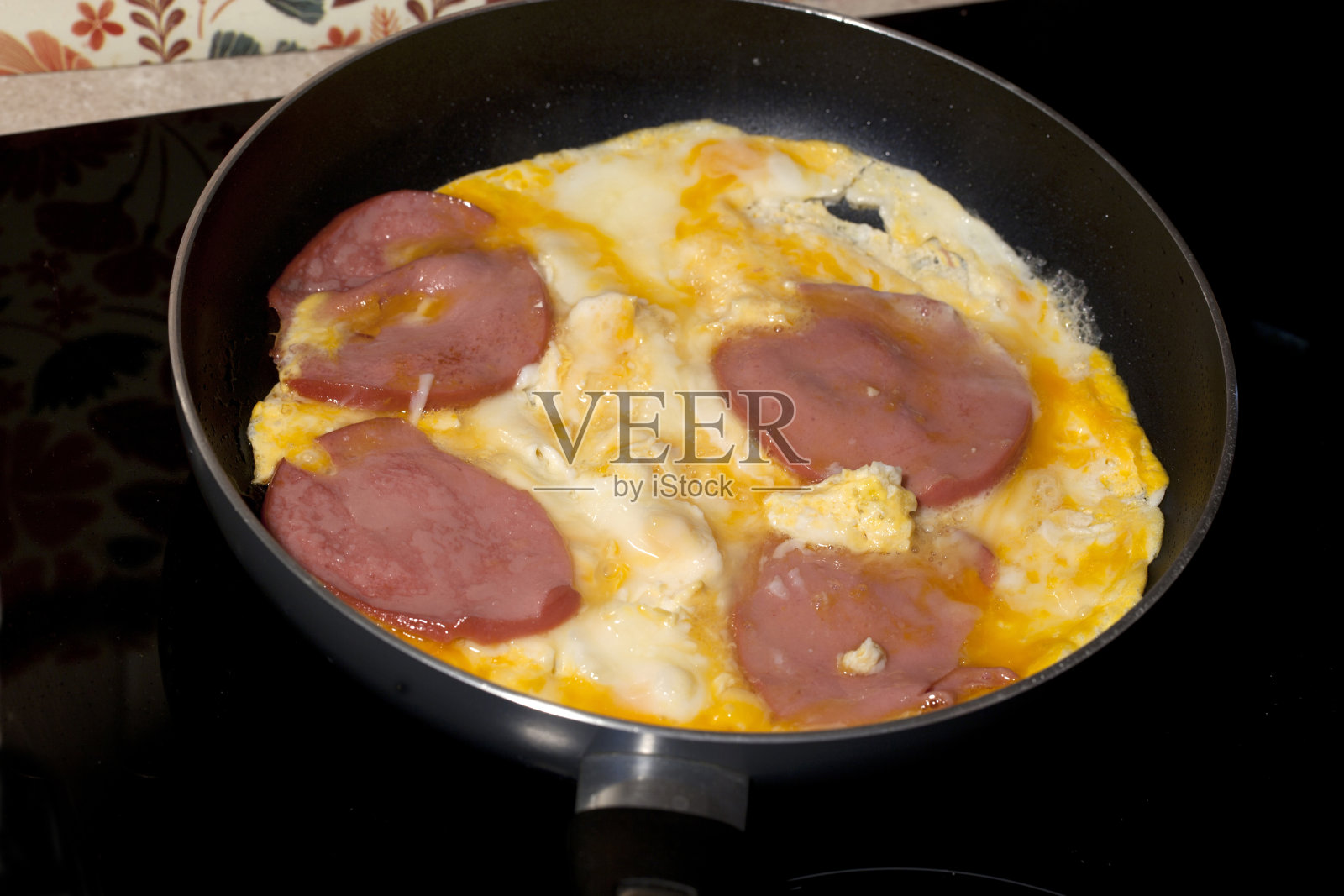 用平底锅煎鸡蛋，黑色平底锅煎香肠，黑色背景照片摄影图片