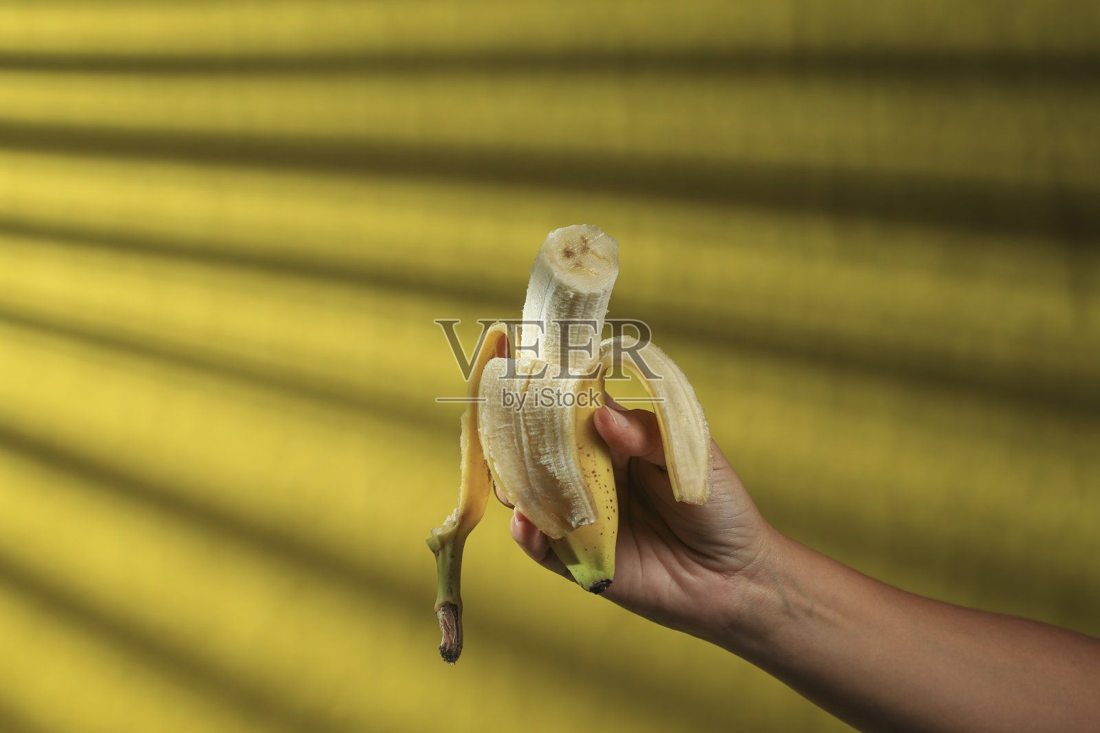 女人的手拿着半剥的香蕉照片摄影图片