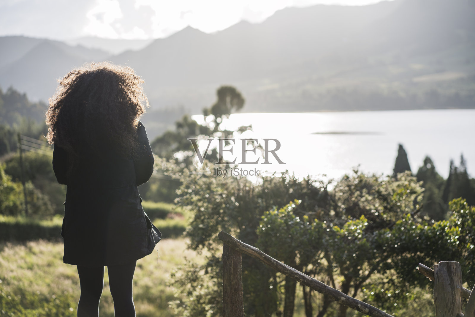 一个非洲女人站在大自然的中间，与周围的风景竞争照片摄影图片