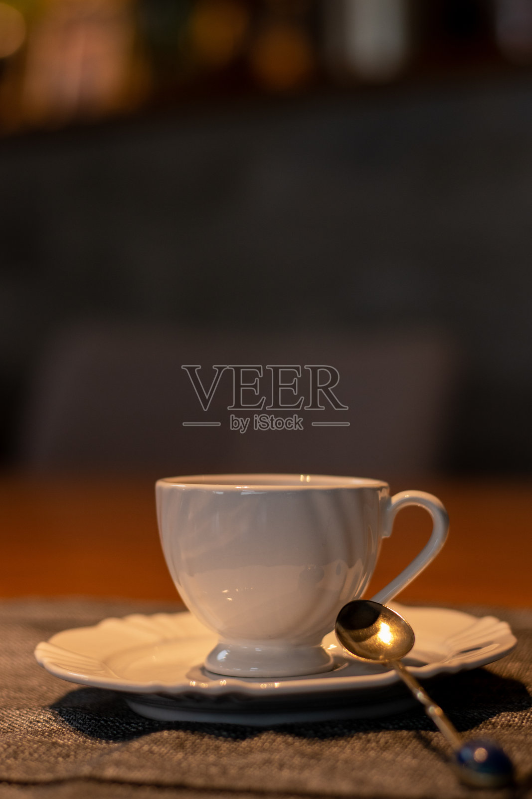 小杯加奶的咖啡，旁边放着一块饼干，放在木桌上。背景是阴天的海和山的景观。照片摄影图片