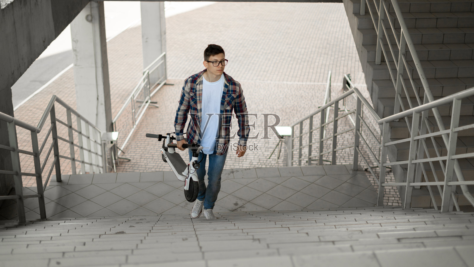 一名学生骑着电动车爬楼梯去学校。现代城市的概念。生态技术的生活方式。照片摄影图片