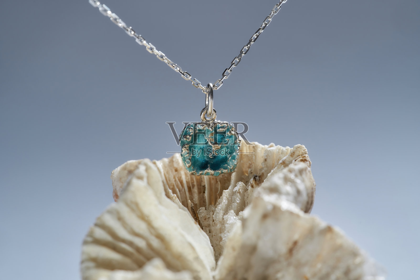 微距镜头的吊坠与链由银和绿松石环氧树脂内部安排贝壳隔离在梯度背景照片摄影图片