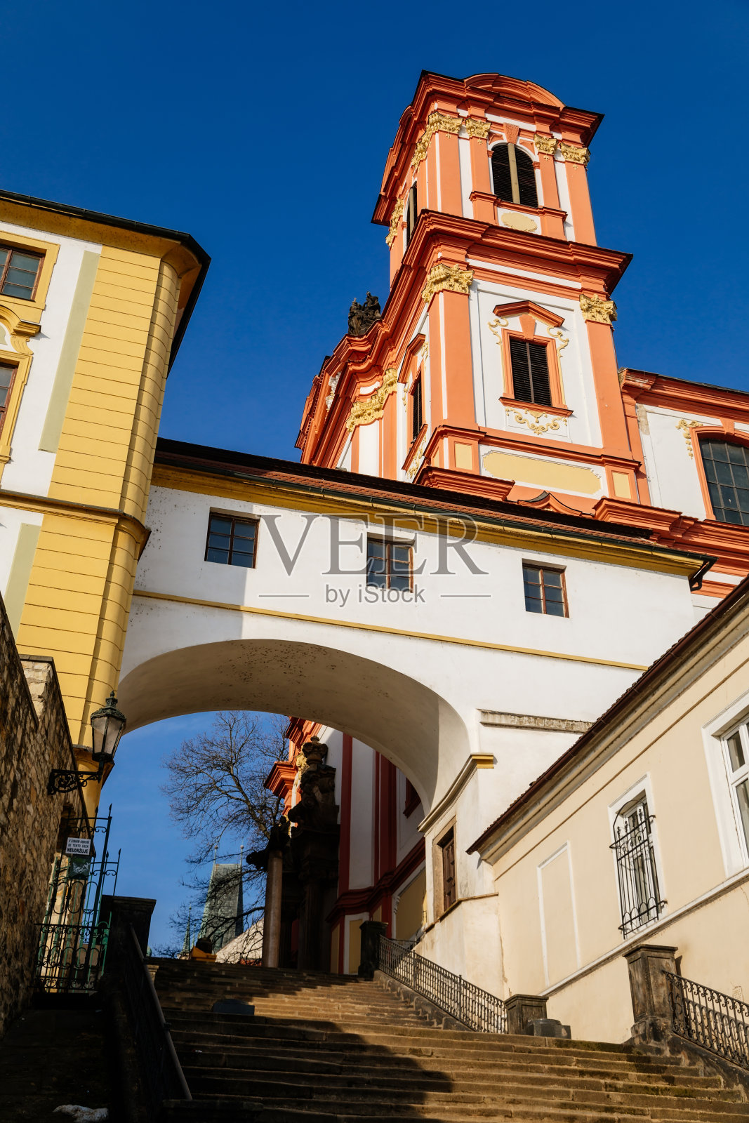 2021年2月20日，捷克共和国，从耶稣会楼梯往下看，耶稣会学院和巴洛克式红白相间的圣母报喜教堂，有塔，Litomerice，阳光明媚，粉刷装饰照片摄影图片
