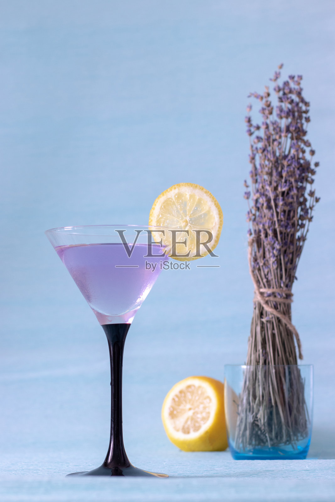蓝色背景上有冰和薰衣草柠檬水的鸡尾酒杯照片摄影图片