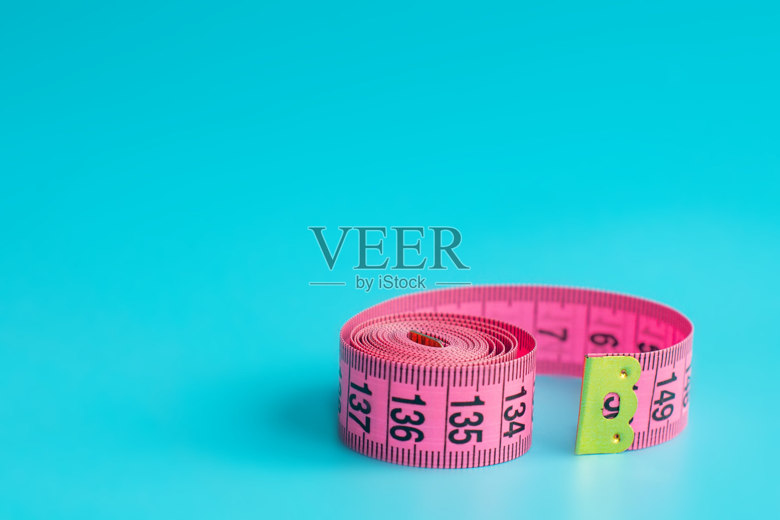 在蓝色背景下用粉红色的皮尺测量照片摄影图片