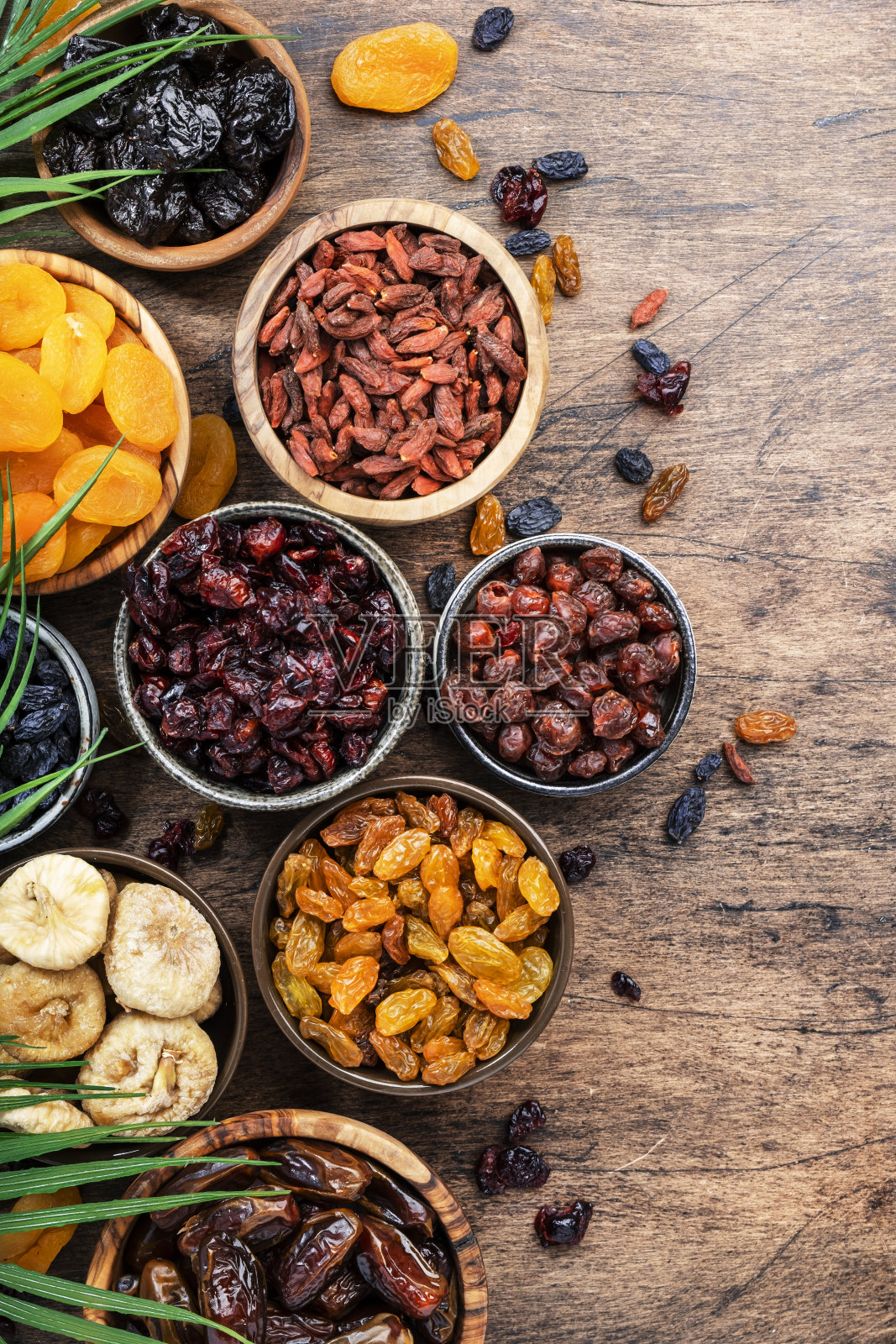 碗里的天然干果。健康食品小吃:晒干的有机混合杏子、无花果、葡萄干、枣子等放在木桌上，俯视图照片摄影图片