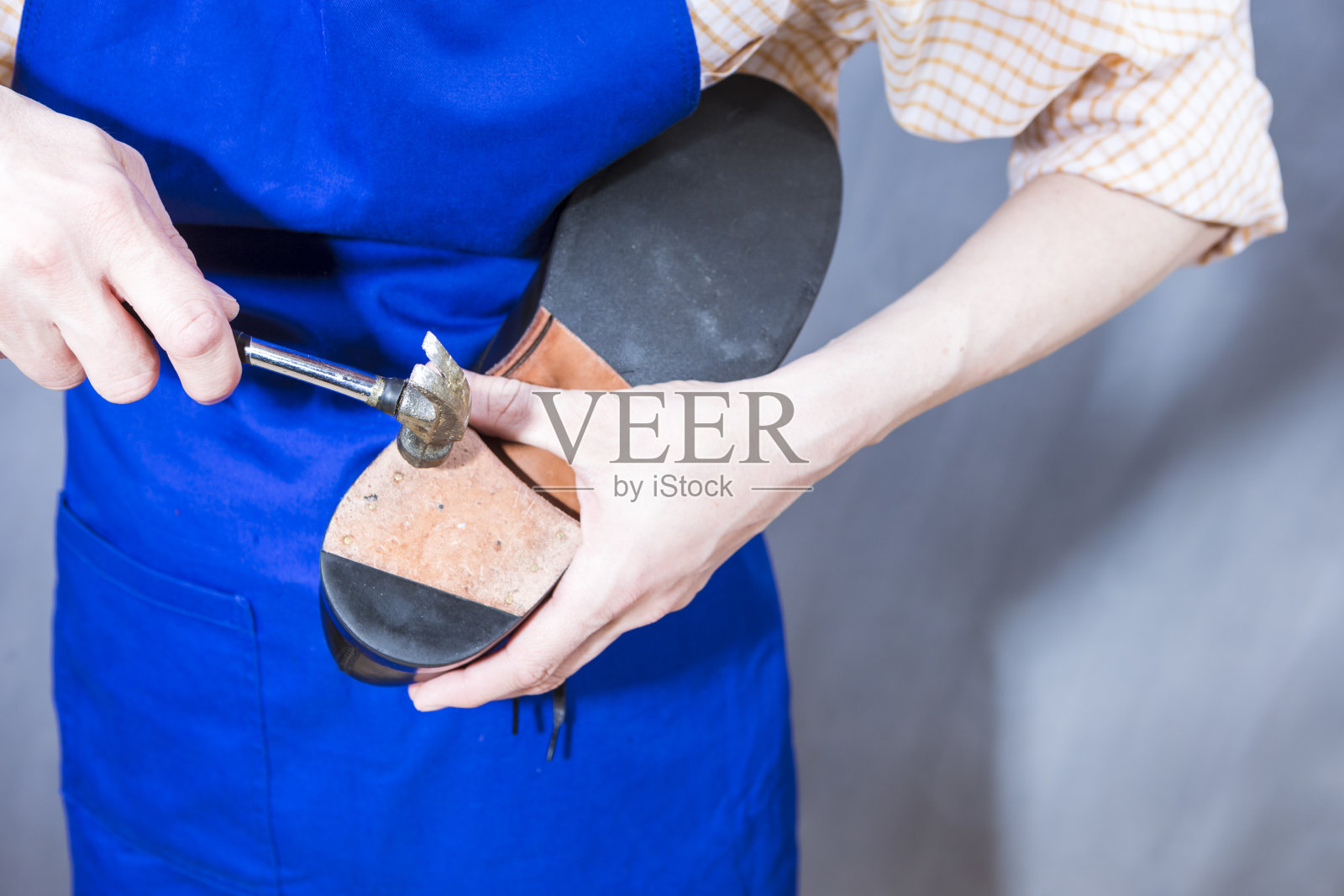 鞋的想法。专业在车间用铁锤修补黑色抛光皮革男鞋底的围裙鞋匠。水平射照片摄影图片