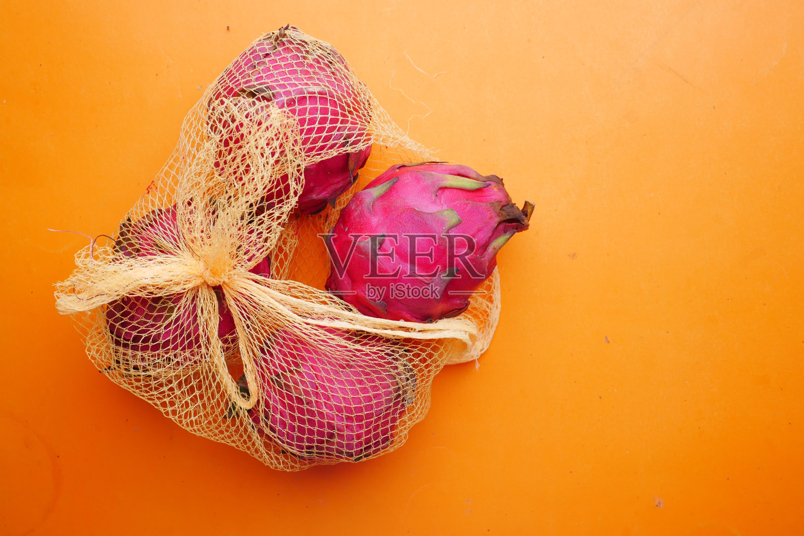 在橙色背景的购物袋里有火龙果照片摄影图片