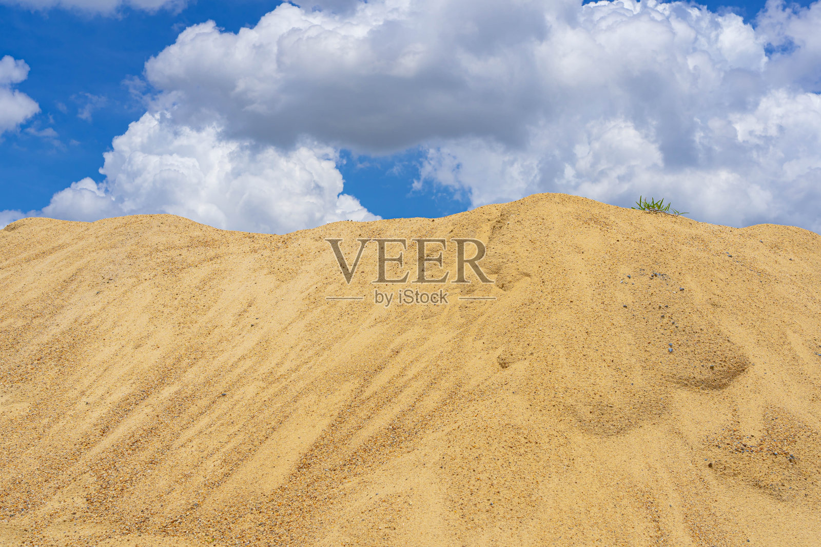 粗沙堆，天空多云。照片摄影图片