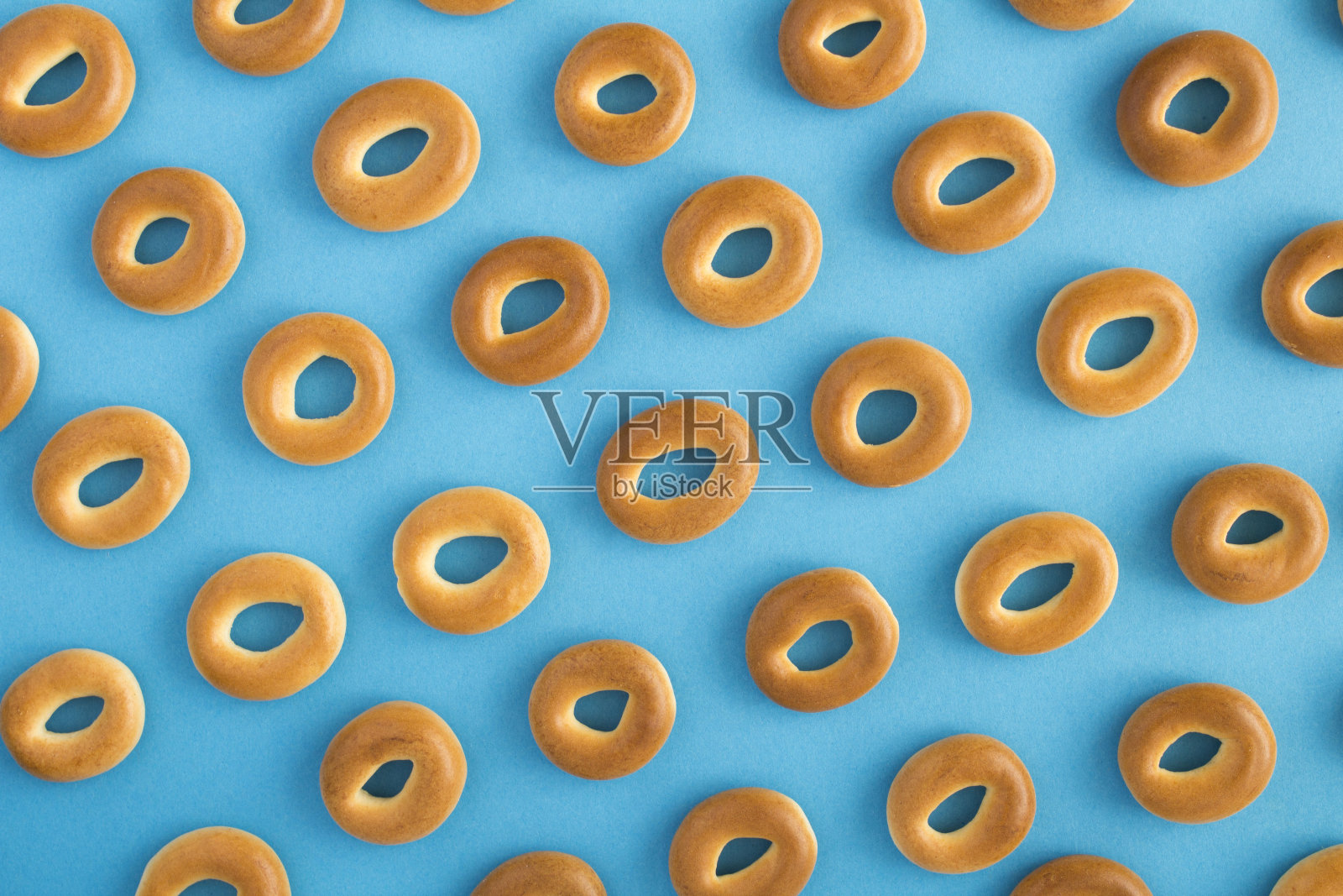 糕点的背景。蓝色背景上的百吉饼。前视图。平的。照片摄影图片