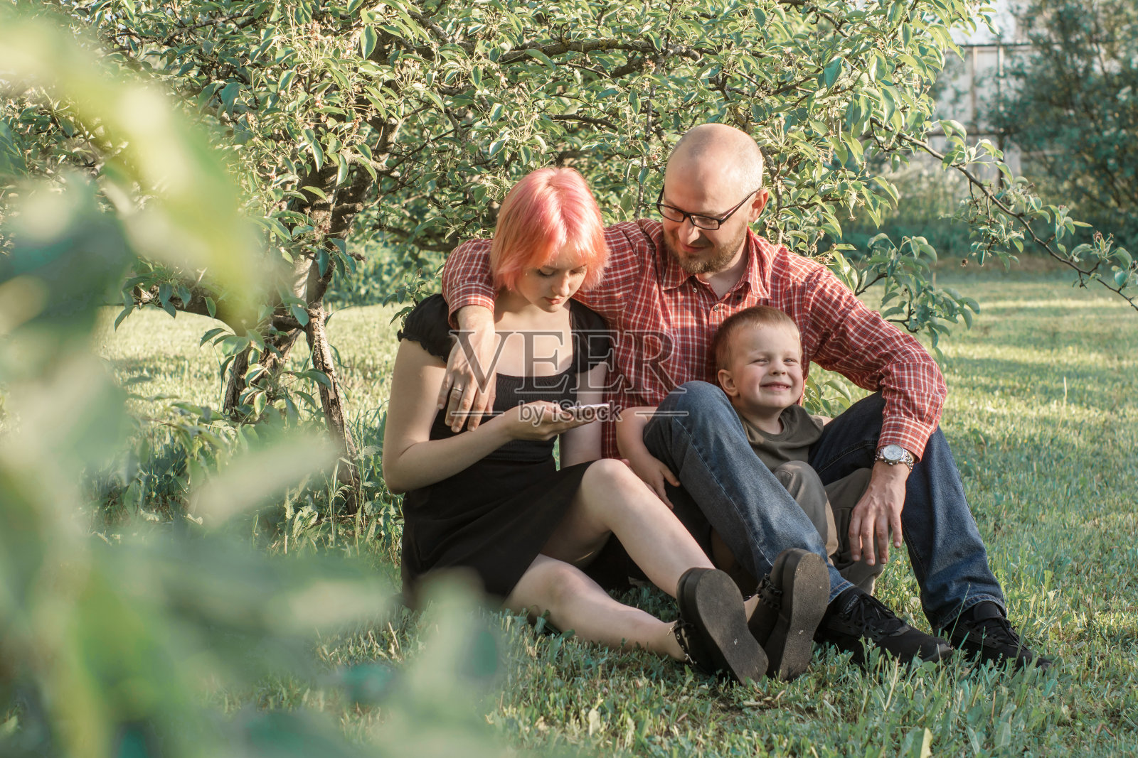 夏天，家人、爸爸和孩子们在公园里放松。一个十几岁的女孩在看她的手机照片摄影图片