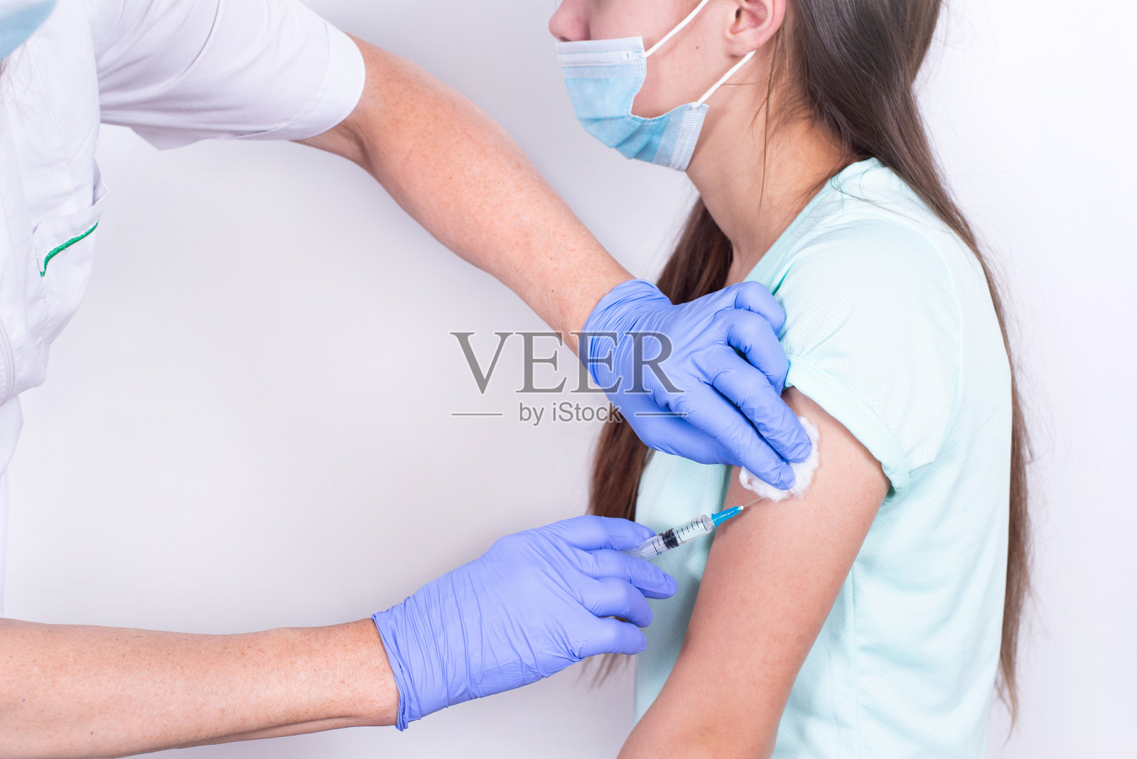 女医生或护士给病人肩膀打针或打疫苗-年轻的女孩。特写镜头。接种流感疫苗、大流行性冠状病毒疫苗。强制预防人对病毒有免疫力。照片摄影图片