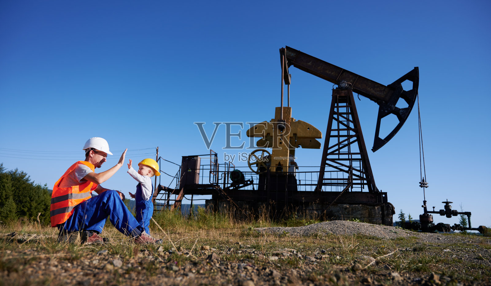 工程师给了小男孩五英镑反对采油站。照片摄影图片