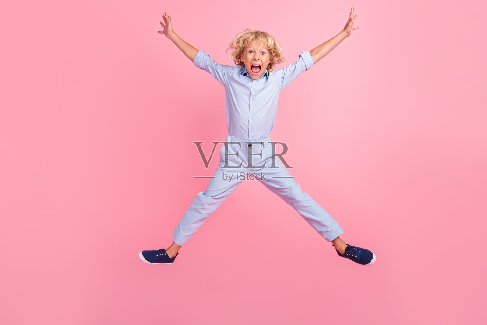有趣的照片兴奋的男生穿着蓝色衬衫跳高微笑孤立的粉红色背景照片摄影图片