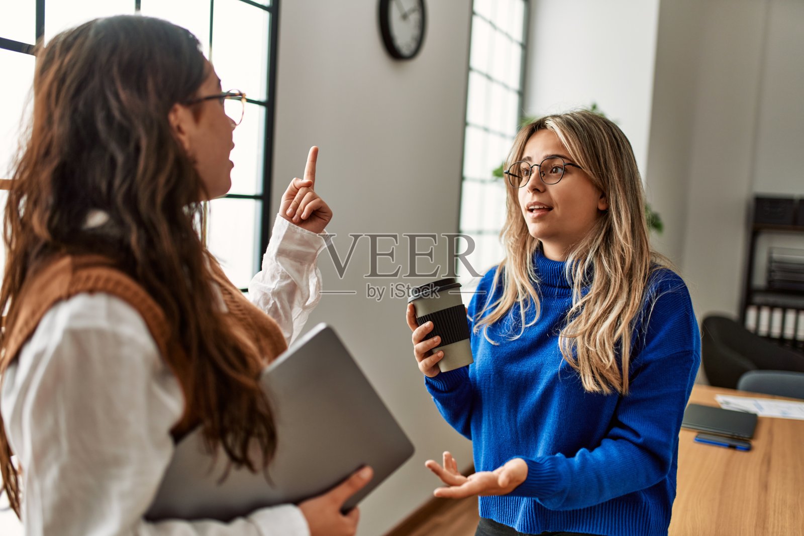 两名女职员在办公室边喝咖啡边聊天。照片摄影图片