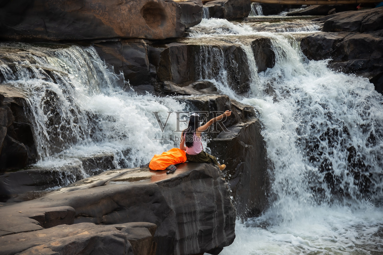 旅行和自由。一个年轻的女人在看丛林里的瀑布。生态旅游概念形象旅游女郎。旅行度假的概念照片摄影图片