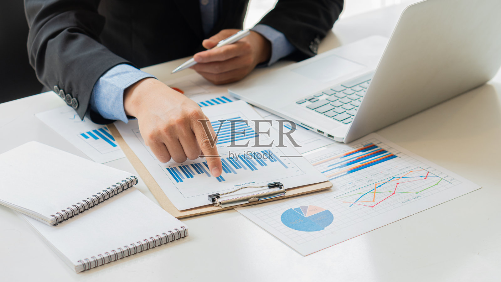 商人工作在图形纸和笔记本电脑使用收入和费用计算器，帐户或财务审计员的报告，计算，家庭财务，投资，经济，储蓄或办公室保险的想法。照片摄影图片